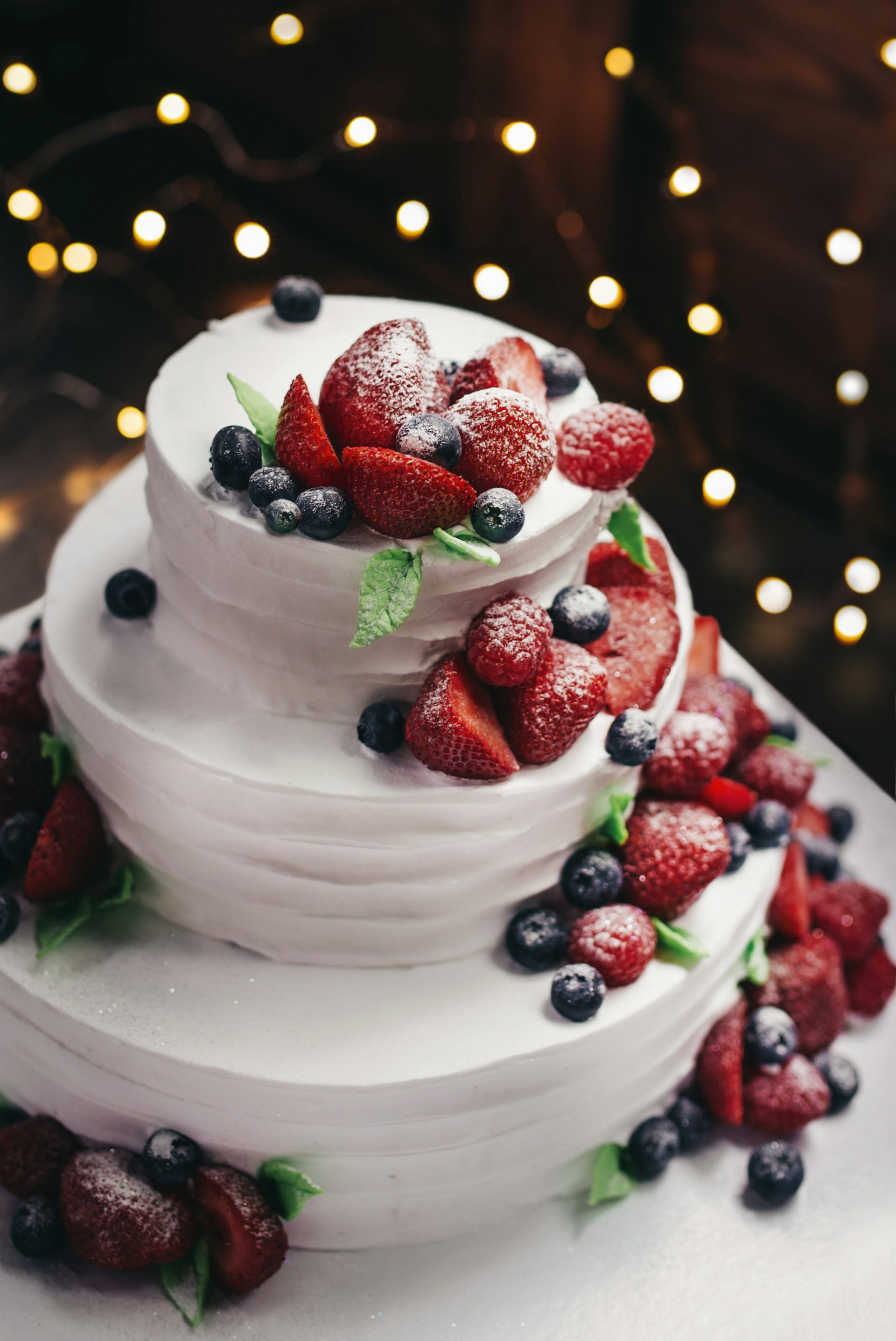 A tiered cake finished with fresh flowers on a linen-draped table